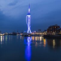 Spinnaker Tower lit blue at night across the harbour