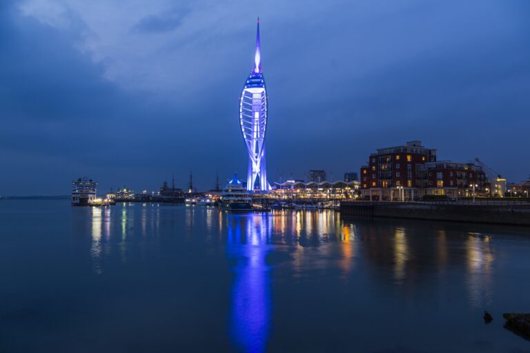 Spinnaker Tower lit blue at night across the harbour